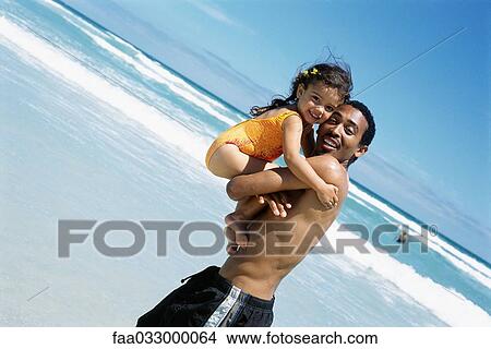 Father carrying daughter at the beach, both smiling at camera View Large Photo Image Picture - Father carrying daughter at the beach, both smiling at camera. Fotosearch