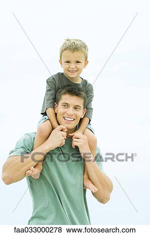 Father carrying son on shoulders, boy looking at camera, both smiling View Large Photo Image Stock Photo - Father carrying son on shoulders, boy looking at camera, both smiling. Fotosearch