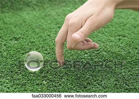 Stock Photograph - Fingers walking up toward small glass globe. Fotosearch