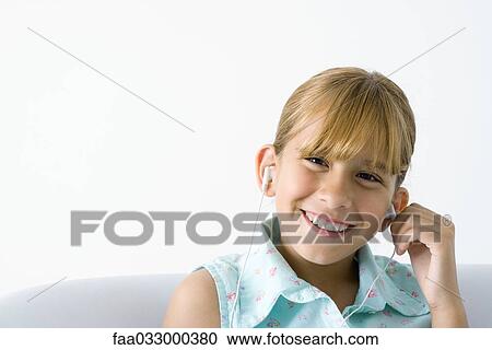 Girl listening to earphones, smiling at camera View Large Photo Image Stock Image - Girl listening to earphones, smiling at camera. Fotosearch