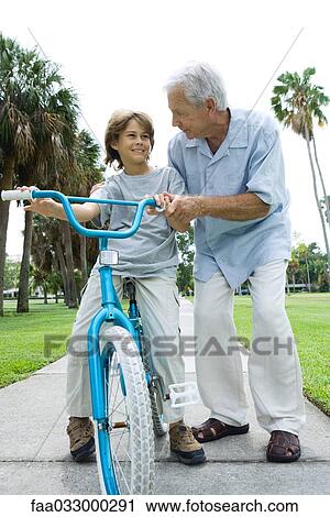 Grandfather teaching grandson to ride bicycle, front view View Large Photo Image Stock Image - Grandfather teaching grandson to ride bicycle, front view. Fotosearch