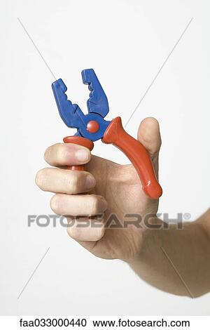 Stock Image - Hand gripping pliers, close-up. Fotosearch