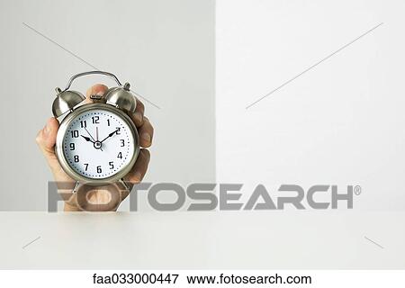 Stock Photo - Hand holding alarm clock. Fotosearch