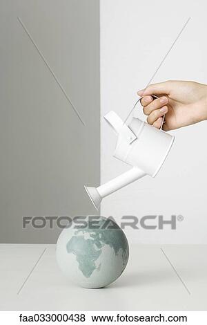 Hand holding watering can over globe View Large Photo Image Stock Photo - Hand holding watering can over globe. Fotosearch