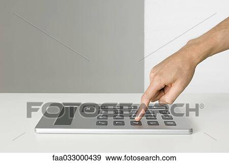 Stock Photo - Hand using oversized calculator. Fotosearch
