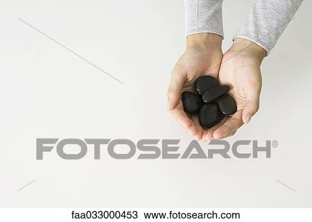 Hands holding black stones, overhead view View Large Photo Image Stock Image - Hands holding black stones, overhead view. Fotosearch