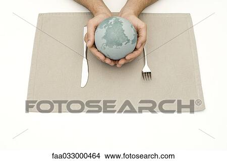 Picture - Hands holding globe over placemat and silverware. Fotosearch