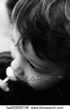 Stock Photograph - Little boy eating a sucker, high angle view, cropped. Fotosearch