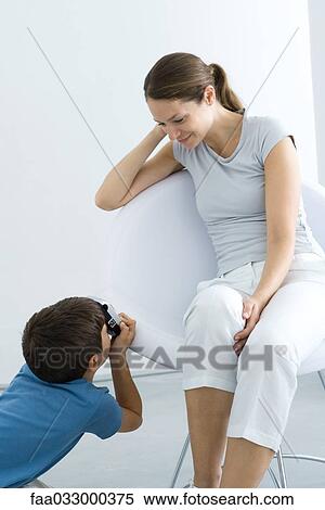 Stock Photography - Little boy photographing his mother with camera. Fotosearch
