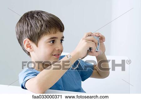 Stock Image - Little boy taking picture with digital camera. Fotosearch