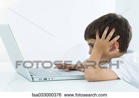 Little boy using laptop computer, holding head, side view View Large Photo Image Stock Photograph - Little boy using laptop computer, holding head, side view. Fotosearch