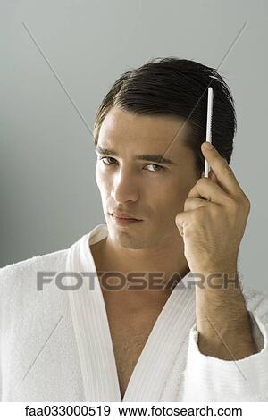 Man combing hair, looking at camera, portrait View Large Photo Image Stock Photo - Man combing hair, looking at camera, portrait. Fotosearch