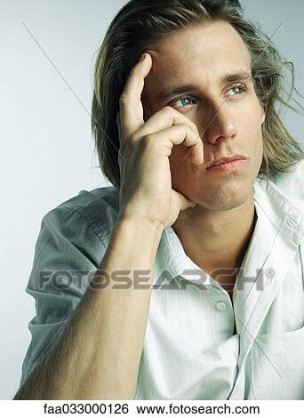 Stock Photograph - Man holding head, looking away, portrait. Fotosearch