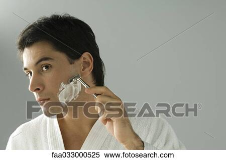 Stock Photography - Man shaving, wearing bathrobe, head tilted. Fotosearch