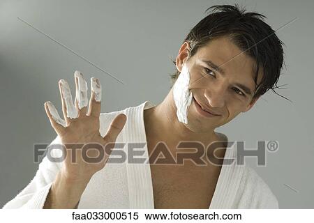 Stock Photography - Man showing his hand with shaving cream on fingers, head tilted, smiling. Fotosearch