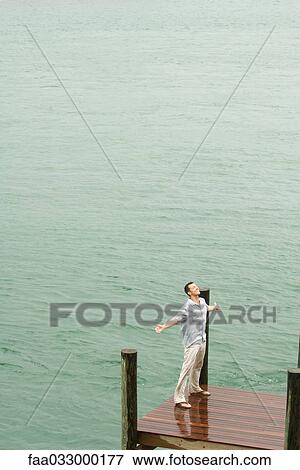 Man standing on dock, getting wet, arms out, high angle view View Large Photo Image Stock Photo - Man standing on dock, getting wet, arms out, high angle view. Fotosearch