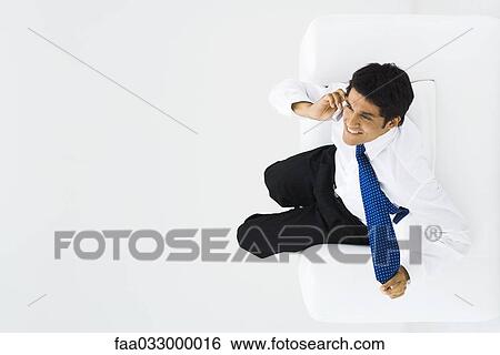 Man using cell phone, tugging at neck tie, overhead view View Large Photo Image Stock Photograph - Man using cell phone, tugging at neck tie, overhead view. Fotosearch