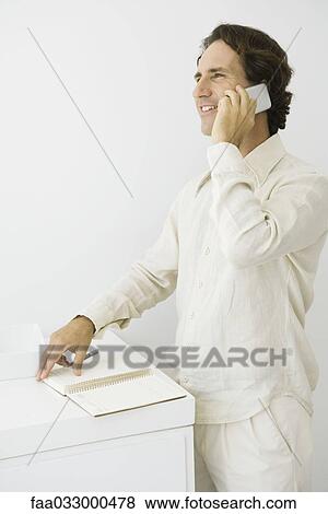 Man using cell phone, turning page in agenda, smiling View Large Photo Image Stock Photo - Man using cell phone, turning page in agenda, smiling. Fotosearch