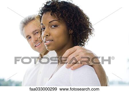 Man with arm around woman, smiling at camera, three-quarter front view View Large Photo Image Stock Photo - Man with arm around woman, smiling at camera, three-quarter front view. Fotosearch