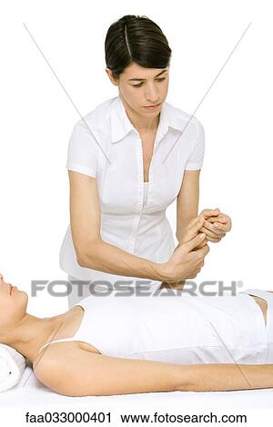 Stock Image - Massage therapist massaging woman's hand. Fotosearch