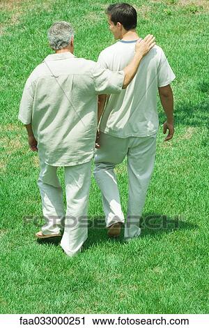 Mature Man Walking With Arm Around Adult Son S Shoulder Outdoors Rear View Stock Image Faa Fotosearch