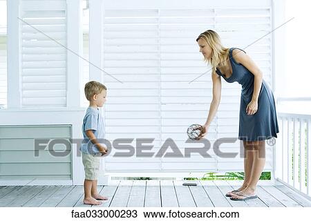 Stock Image - Mother and son face to face, playing catch, side view. Fotosearch
