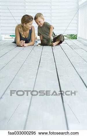 Stock Photography - Mother and son on porch together, smiling at each other, boy with hand in jar, low angle view. Fotosearch