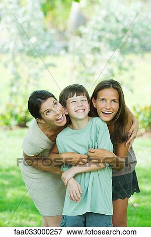 Mother embracing son and teen daughter, all smiling and looking up View Large Photo Image Stock Photo - Mother embracing son and teen daughter, all smiling and looking up. Fotosearch
