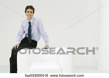 Professional man sitting on armchair, smiling at camera View Large Photo Image Stock Photograph - Professional man sitting on armchair, smiling at camera. Fotosearch