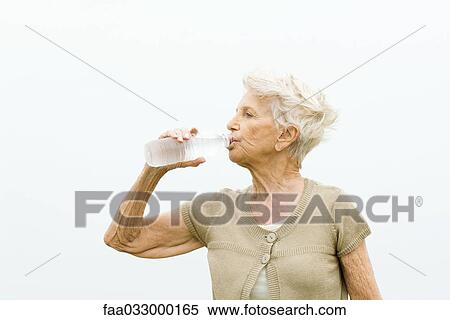 Stock Photography - Senior woman drinking bottle of cold water. Fotosearch