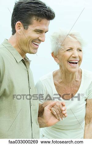 Senior woman holding adult son's hand, both looking away, smiling View Large Photo Image Stock Photo - Senior woman holding adult son's hand, both looking away, smiling. Fotosearch