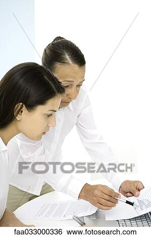 Senior woman in office, discussing document with younger colleague View Large Photo Image Stock Photograph - Senior woman in office, discussing document with younger colleague. Fotosearch