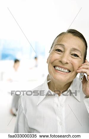 Stock Photography - Senior woman using cell phone, smiling at camera. Fotosearch