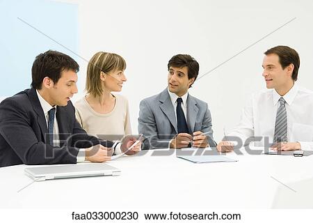 Team of professionals sitting together at table, discussing, looking at each other View Large Photo Image Stock Image - Team of professionals sitting together at table, discussing, looking at each other. Fotosearch