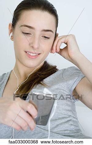 Stock Photo - Teen girl listening to MP3 player, smiling, looking down. Fotosearch