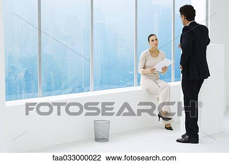 Two business associates by window, having conversation View Large Photo Image Stock Image - Two business associates by window, having conversation. Fotosearch