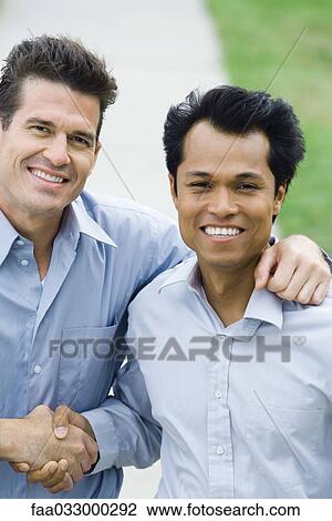 Two businessmen shaking hands, both smiling at camera, high angle view View Large Photo Image Stock Image - Two businessmen shaking hands, both smiling at camera, high angle view. Fotosearch