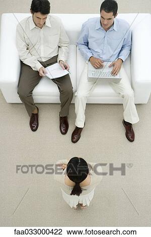 Woman being interviewed by two men, one man holding laptop, high angle view View Large Photo Image Stock Image - Woman being interviewed by two men, one man holding laptop, high angle view. Fotosearch