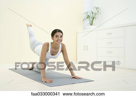 Stock Image - Woman down on all fours, exercising, smiling at camera. Fotosearch
