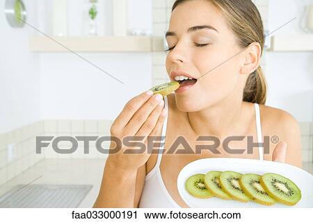 Woman eating fresh kiwi slices, eyes closed View Large Photo Image Stock Image - Woman eating fresh kiwi slices, eyes closed. Fotosearch