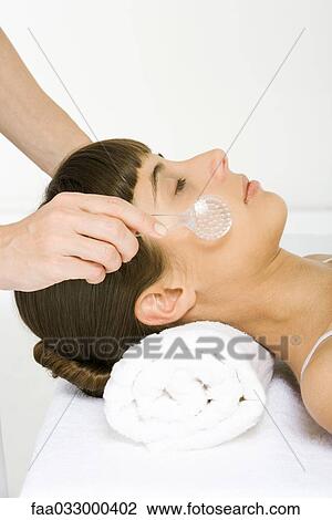 Stock Image - Woman having face exfoliated, eyes closed, side view. Fotosearch