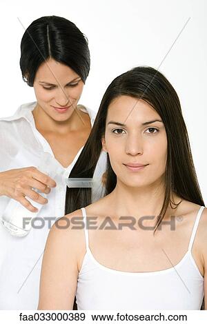 Stock Photo - Woman having her hair styled, smiling at camera. Fotosearch