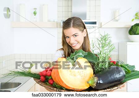 Woman holding tray of fresh vegetables, smiling at camera View Large Photo Image Stock Photo - Woman holding tray of fresh vegetables, smiling at camera. Fotosearch