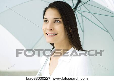 Stock Photo - Woman holding umbrella, smiling, portrait. Fotosearch