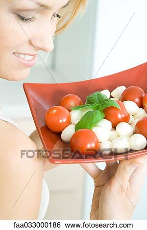 Woman holding up tomato mozzarella salad, smiling, cropped view View Large Photo Image Stock Photograph - Woman holding up tomato mozzarella salad, smiling, cropped view. Fotosearch