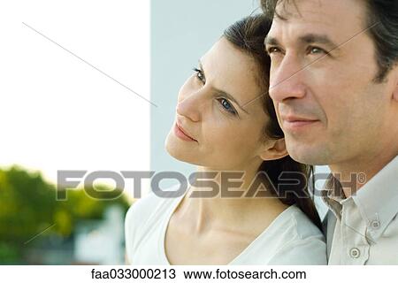 Stock Image - Woman leaning her head against man's cheek, both looking away. Fotosearch