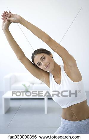 Woman leaning to one side, arms raised, smiling at camera View Large Photo Image Stock Photograph - Woman leaning to one side, arms raised, smiling at camera. Fotosearch