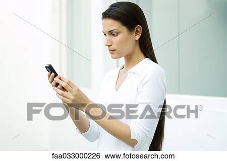 Woman looking at cell phone, side view View Large Photo Image Stock Photograph - Woman looking at cell phone, side view. Fotosearch