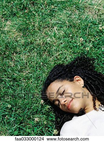 Woman lying on her back on the grass, head and shoulders, eyes closed View Large Photo Image Picture - Woman lying on her back on the grass, head and shoulders, eyes closed. Fotosearch