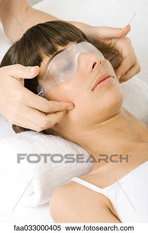 Stock Photography - Woman receiving face massage, wearing eye mask. Fotosearch